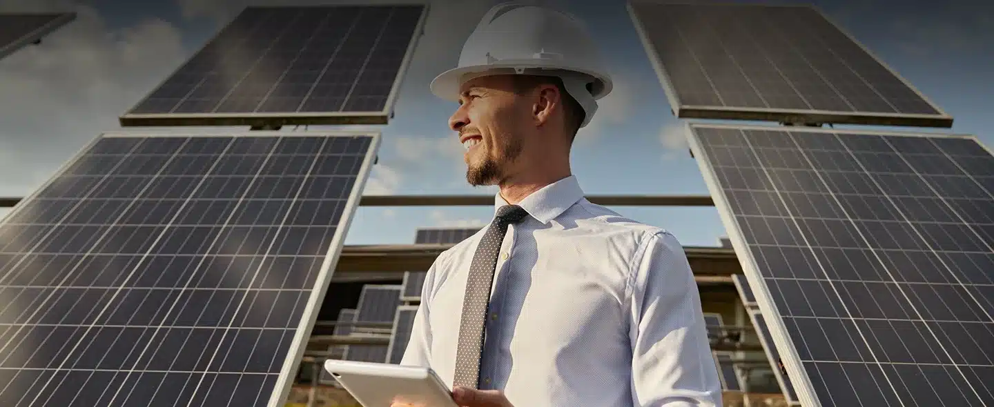 Engenheiro usando tablet em campo com painéis solares trabalhando para investidor de energia solar