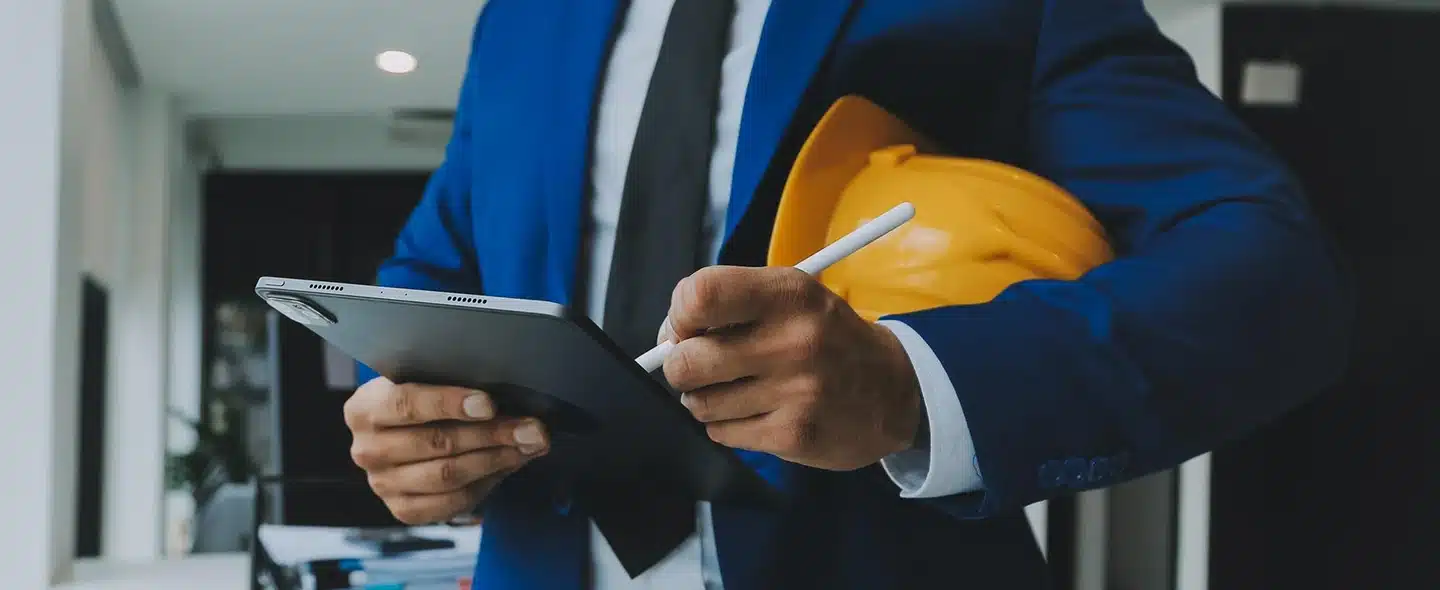 Homem de terno azul segurando um tablet e assinando plano de gestão de créditos para usinas