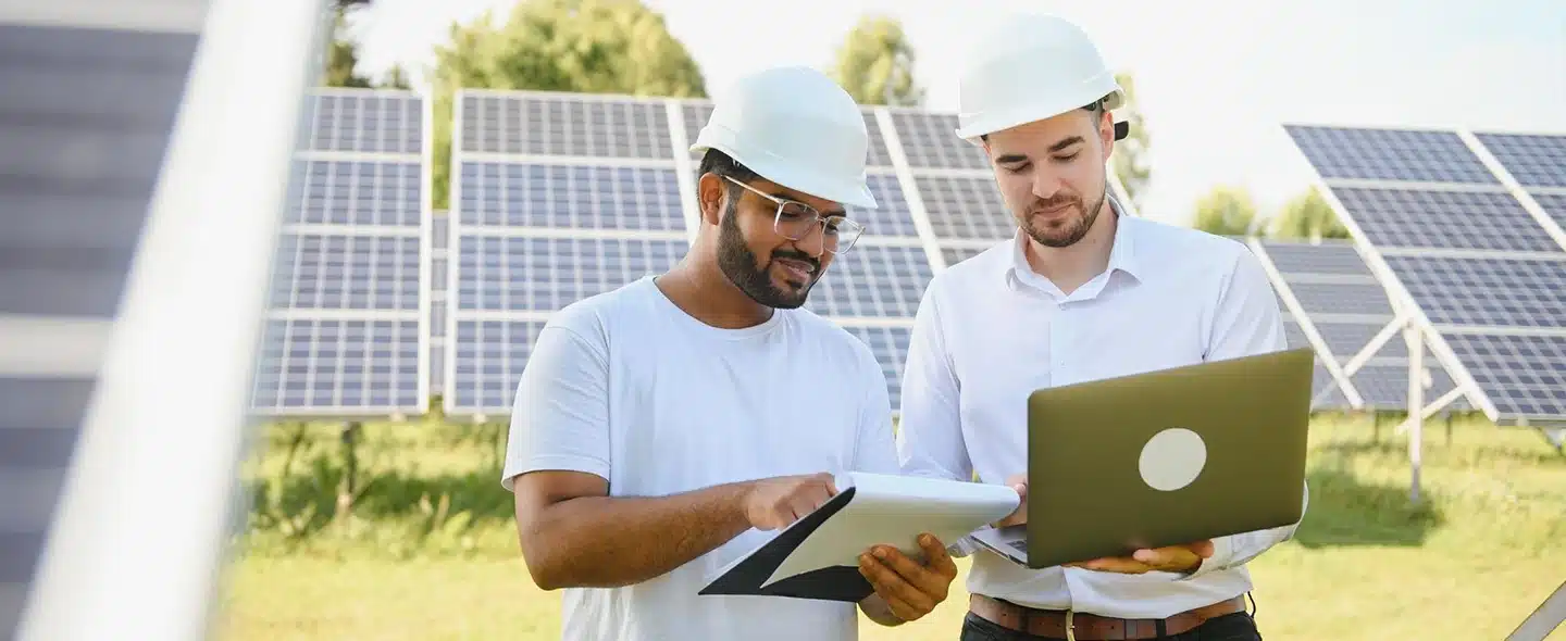 Engenheiros na estação de energia solar com painel solar ao fundo fazendo a gestão de usina