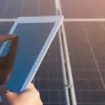 Imagem de mão da masculina segurando tablet enquanto faz a gestão de créditos de energia solar